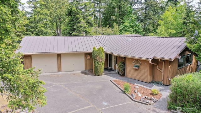 view of front of property with metal roof, driveway, an attached garage, and a standing seam roof