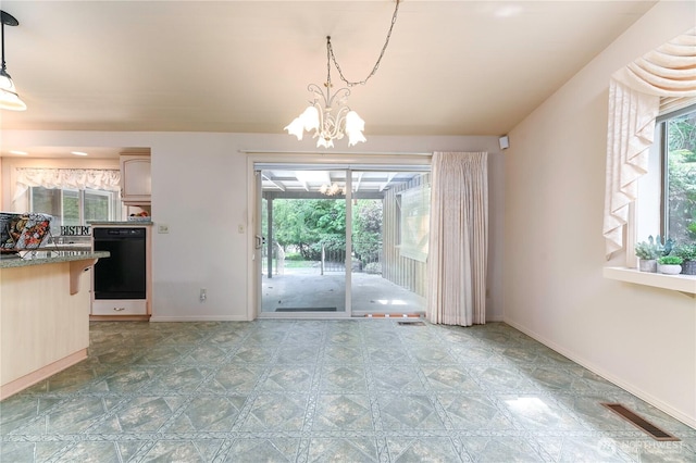 unfurnished dining area featuring a chandelier and baseboards