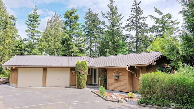 view of front of home with metal roof, a garage, and asphalt driveway
