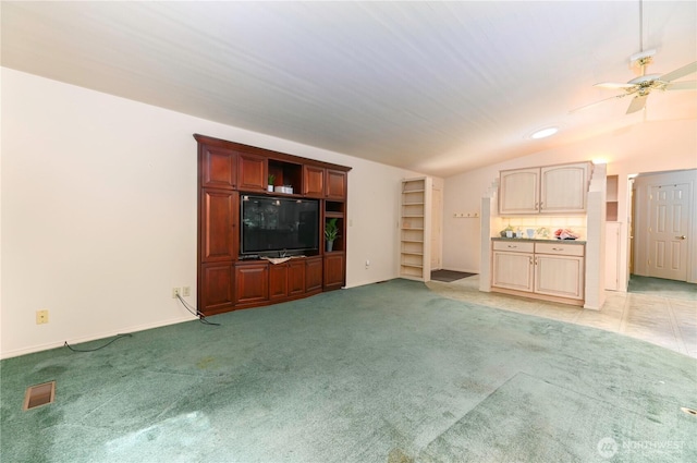 unfurnished living room with vaulted ceiling, light colored carpet, ceiling fan, and baseboards