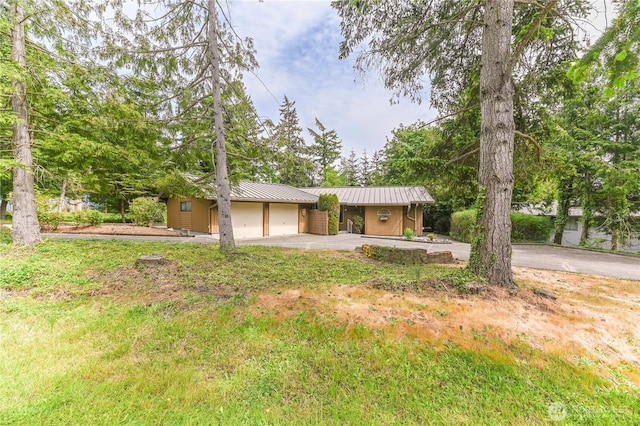 view of front of property with asphalt driveway, a garage, metal roof, and a standing seam roof