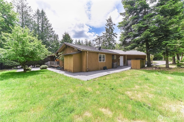 rear view of house with a lawn, a deck, and metal roof