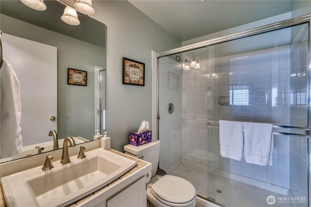 full bath featuring toilet, a stall shower, and vanity