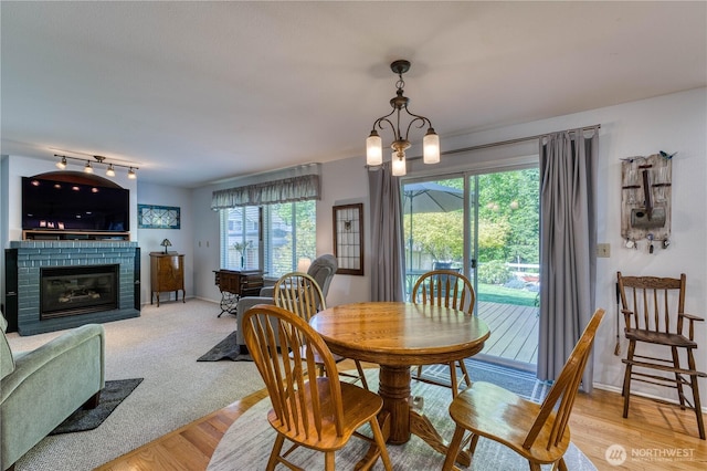 dining area with plenty of natural light, a fireplace, wood finished floors, and baseboards