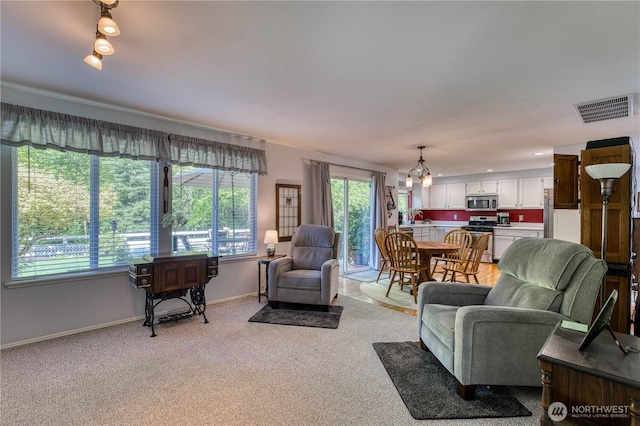 living room with baseboards, light carpet, and a chandelier