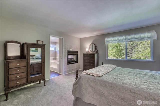 carpeted bedroom featuring a tiled fireplace, multiple windows, and baseboards