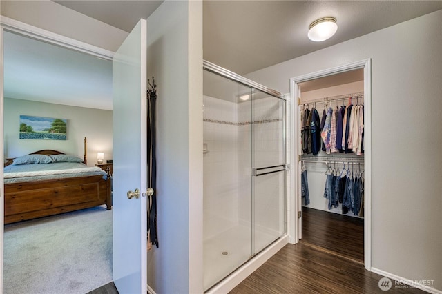 full bathroom featuring a shower stall, ensuite bathroom, a spacious closet, and baseboards