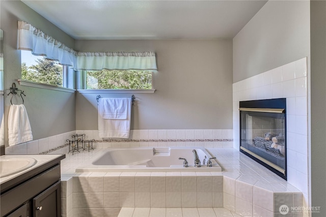 full bathroom featuring a bath, a fireplace, and vanity