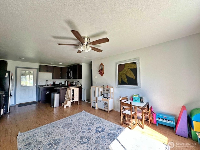 living room with ceiling fan, dark wood finished floors, and a textured ceiling