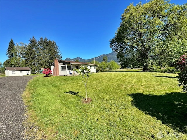 view of front of house with a mountain view, a front lawn, and a chimney