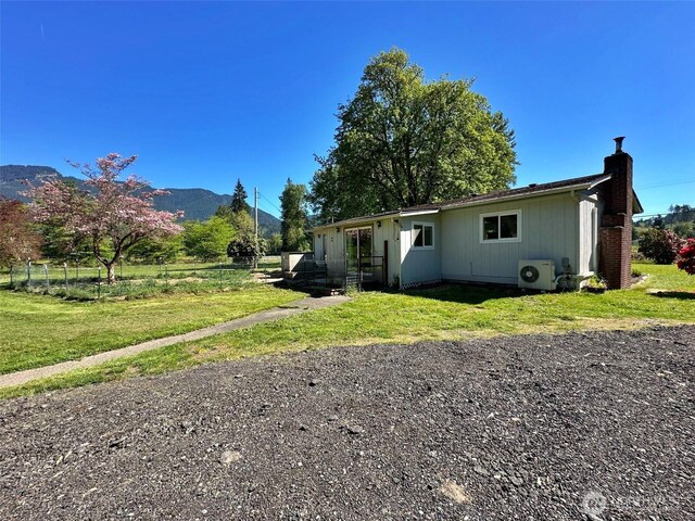 view of front of property with a front lawn, a mountain view, ac unit, and a chimney