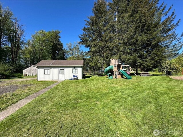 view of grassy yard with a playground and an outdoor structure