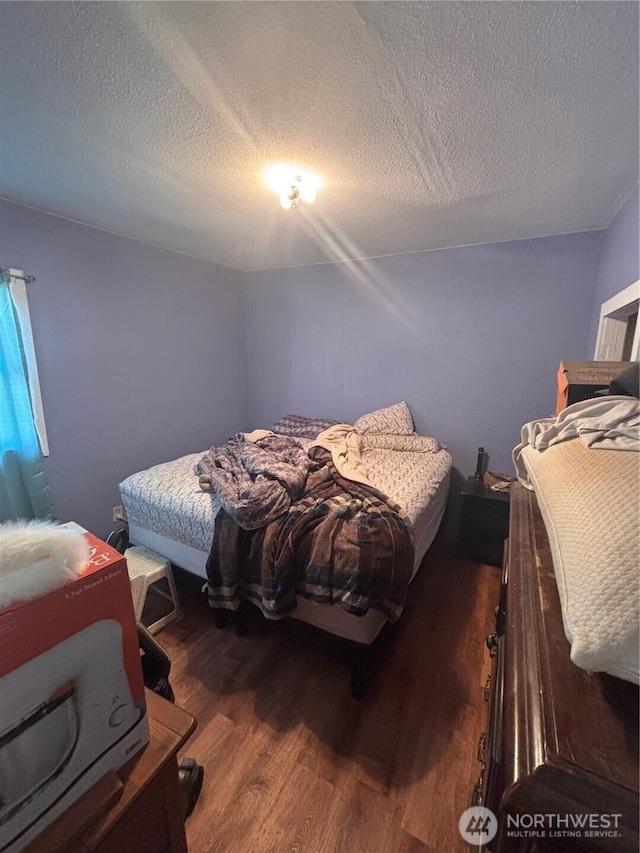 bedroom with a textured ceiling and wood finished floors