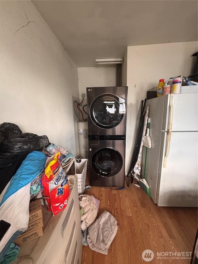 washroom with electric water heater, laundry area, stacked washing maching and dryer, and wood finished floors