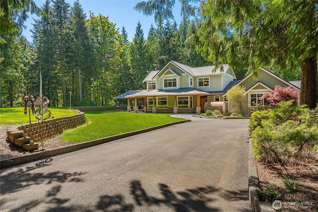 view of front of home featuring covered porch, asphalt driveway, and stone siding