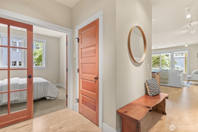corridor featuring wood finished floors, baseboards, and rail lighting
