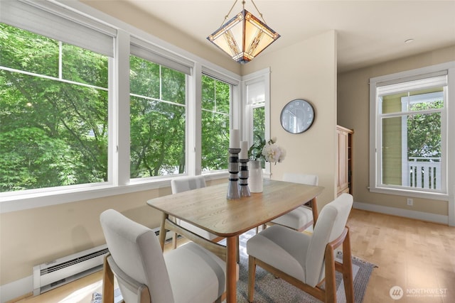 dining room featuring baseboard heating, light wood-style flooring, and baseboards