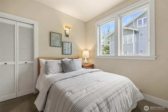 bedroom with dark carpet, a closet, and baseboards