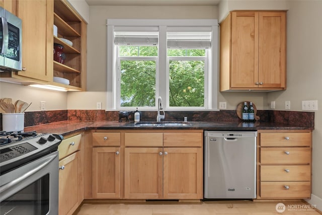 kitchen featuring appliances with stainless steel finishes, a sink, dark stone countertops, and open shelves