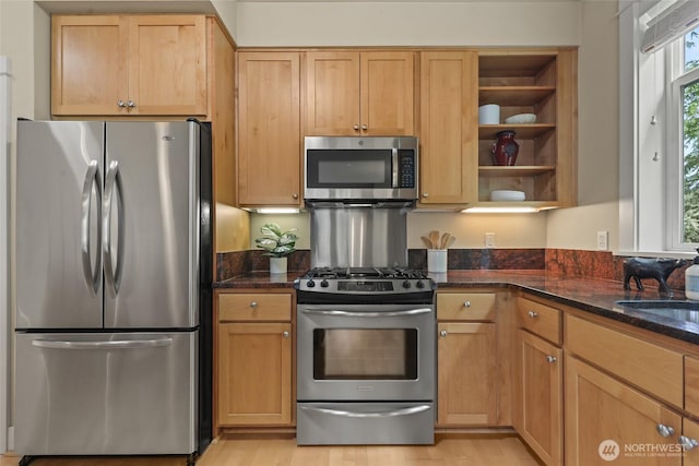 kitchen with appliances with stainless steel finishes, dark stone counters, open shelves, and light wood-type flooring