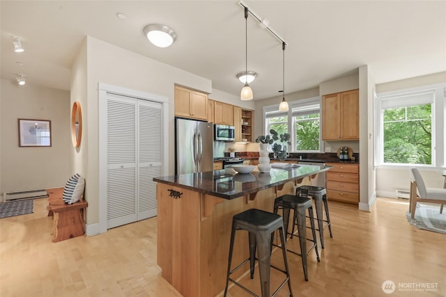 kitchen with stainless steel appliances, a baseboard heating unit, a breakfast bar area, a center island, and light wood-style flooring