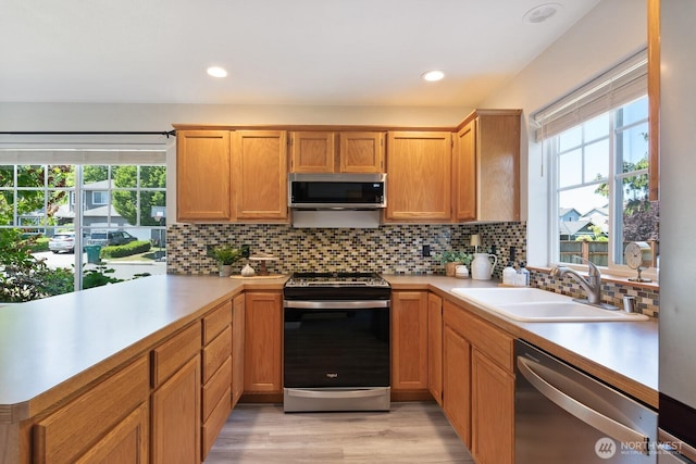 3828 Sutton Pl, Anacortes, WA 98221 - kitchen with appliances with stainless steel finishes, a sink, light countertops, decorative backsplash, and light wood-type flooring