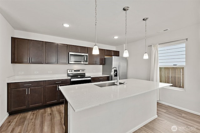 9206 Conine St SE, Yelm, WA 98597 - kitchen featuring stainless steel appliances, a sink, light wood-style flooring, dark brown cabinets, and pendant lighting
