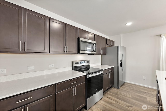 9206 Conine St SE, Yelm, WA 98597 - kitchen with appliances with stainless steel finishes, dark brown cabinetry, light wood-style flooring, light countertops, and recessed lighting