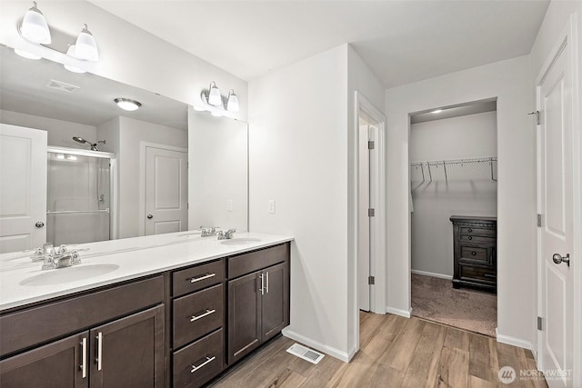 9206 Conine St SE, Yelm, WA 98597 - full bath featuring wood finished floors, a shower stall, double vanity, a walk in closet, and baseboards
