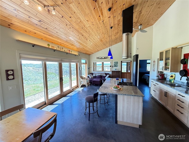 kitchen with wood ceiling, a breakfast bar area, a sink, open floor plan, and a kitchen island
