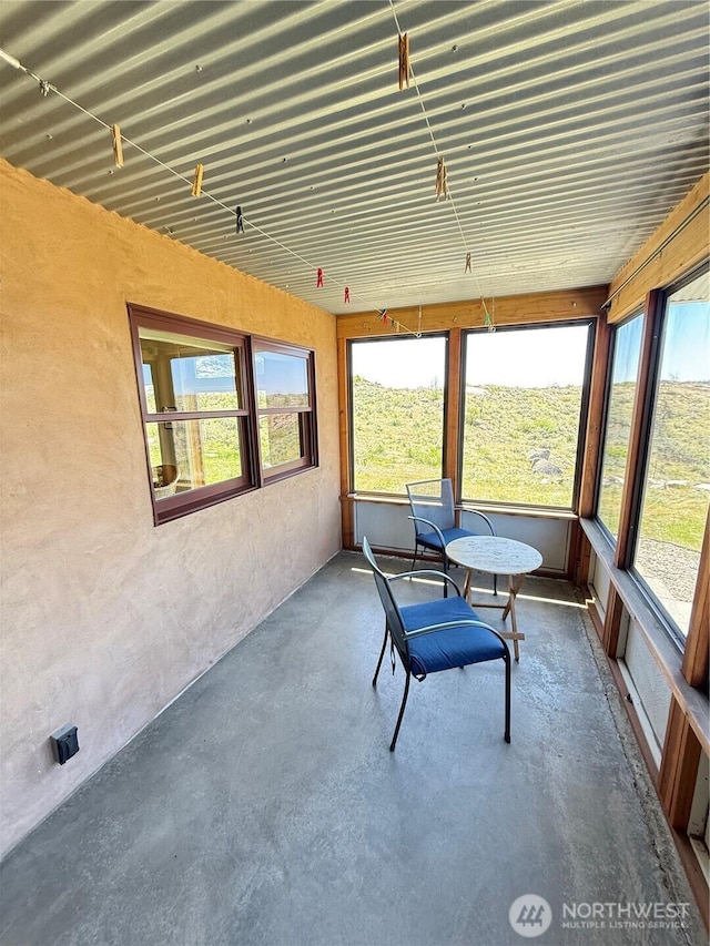 sunroom with unfinished concrete floors and healthy amount of natural light