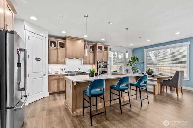 19507 81st Pl NE Unit 3, Kenmore, WA 98028 - kitchen with stainless steel appliances, light wood-style floors, light countertops, glass insert cabinets, and a center island with sink