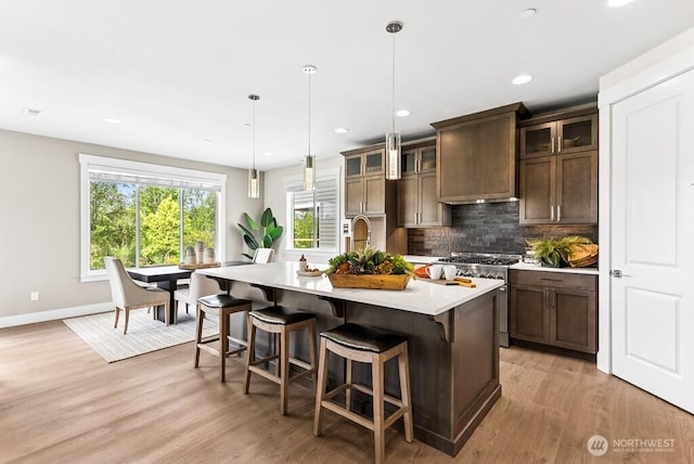 19507 81st Pl NE Unit 3, Kenmore, WA 98028 - kitchen featuring high end range, light countertops, light wood-type flooring, decorative backsplash, and an island with sink