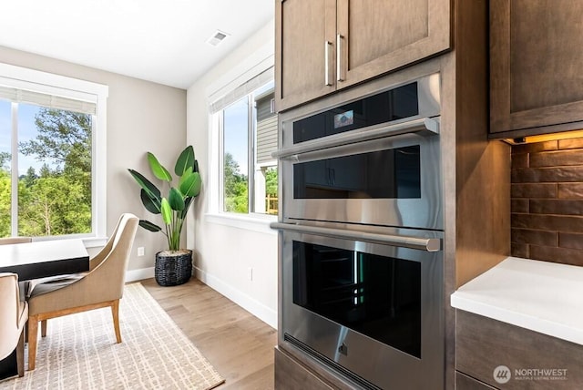 19507 81st Pl NE Unit 3, Kenmore, WA 98028 - kitchen featuring double oven, light wood-type flooring, light countertops, and dark brown cabinetry