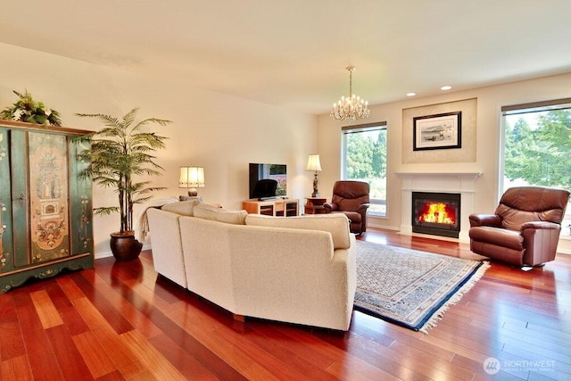 living area featuring an inviting chandelier, dark wood-type flooring, a fireplace with flush hearth, and recessed lighting