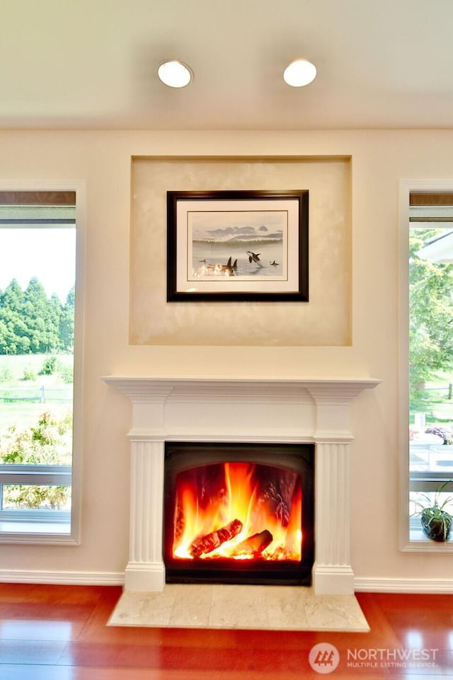 details with baseboards, a fireplace with flush hearth, and wood finished floors