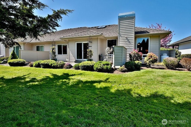 back of house featuring a chimney and a lawn