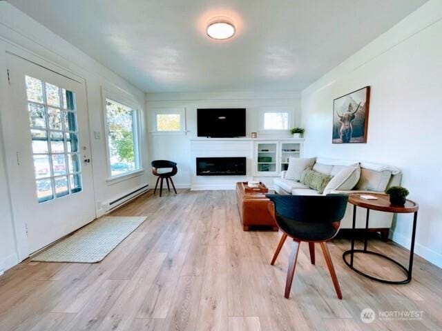 living room with a baseboard heating unit, healthy amount of natural light, light wood-style floors, and a fireplace
