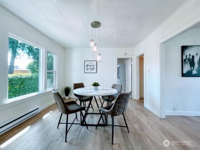 dining area with a baseboard radiator, light wood-style floors, and baseboards