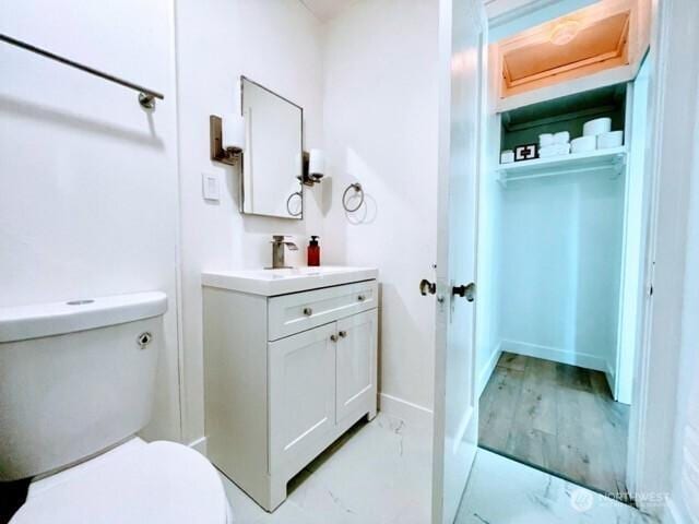 bathroom featuring toilet, vanity, and baseboards