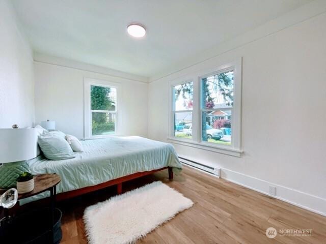 bedroom featuring a baseboard radiator, wood finished floors, and baseboards