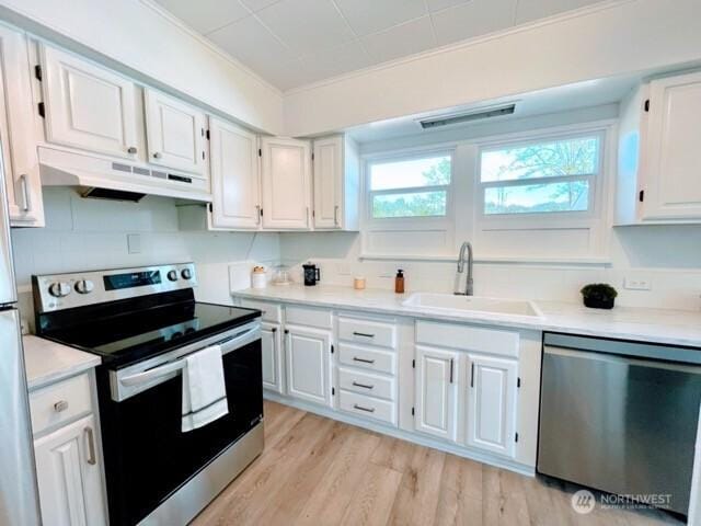kitchen featuring stainless steel appliances, under cabinet range hood, a sink, white cabinets, and light wood-style flooring