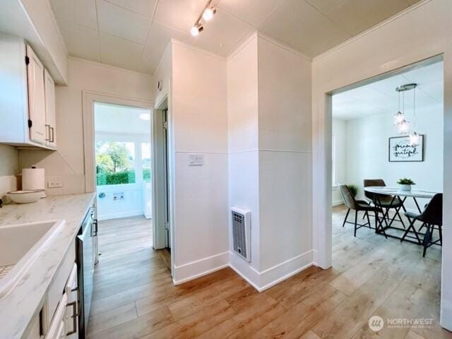hall with light wood-style flooring, a chandelier, baseboards, and a sink