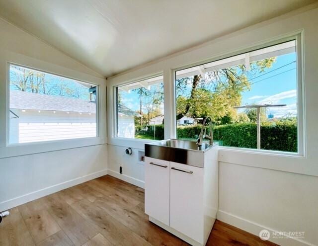 unfurnished sunroom with lofted ceiling and a sink