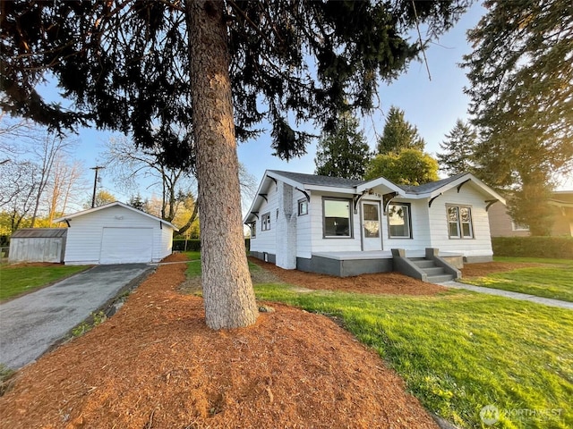 bungalow featuring an outdoor structure, driveway, a front lawn, and a detached garage