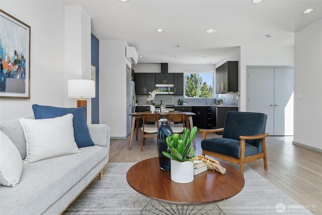 living room featuring light wood finished floors, recessed lighting, and baseboards