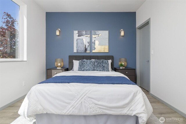 bedroom with wood finished floors and an accent wall