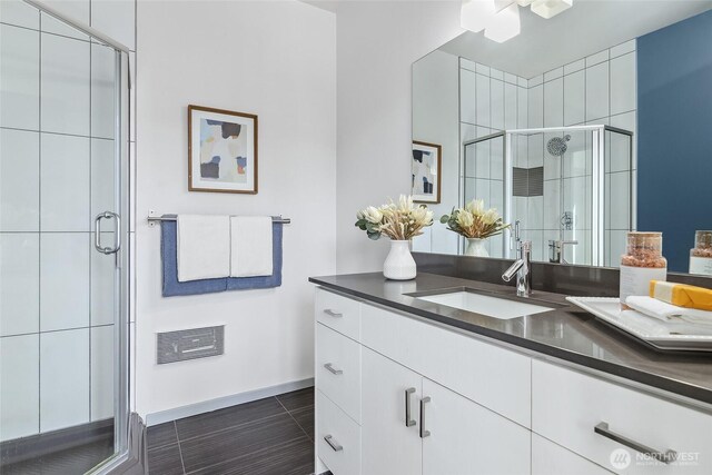 bathroom with a stall shower, vanity, and baseboards
