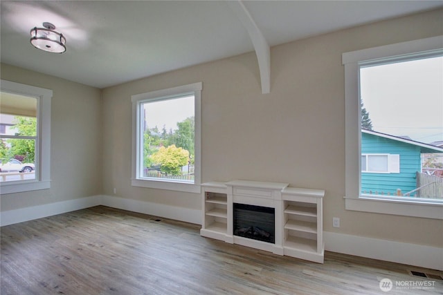 1813 10th St, Anacortes, WA 98221 - unfurnished living room with wood finished floors, a glass covered fireplace, and baseboards