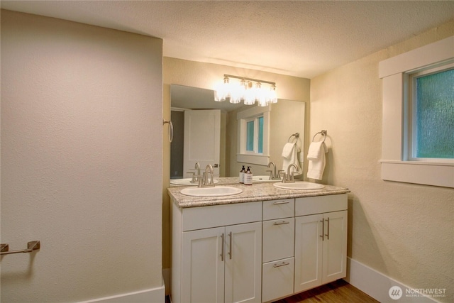 1813 10th St, Anacortes, WA 98221 - bathroom with double vanity, a textured ceiling, baseboards, and wood finished floors